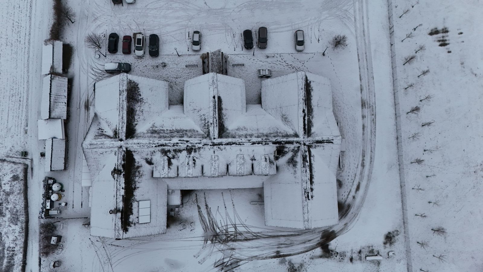 a close up of an old building Aerial view of a snow-covered commercial building and parking lot in winter