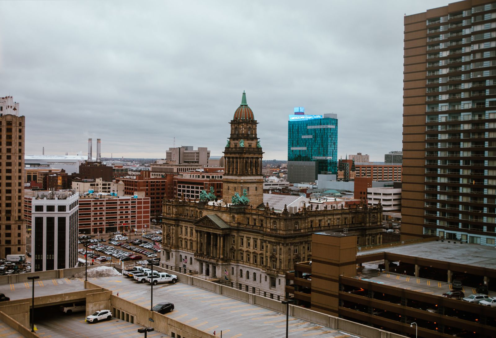 a tall building in a city Aerial view of downtown Detroit office buildings, parking structures and flat commercial roofs