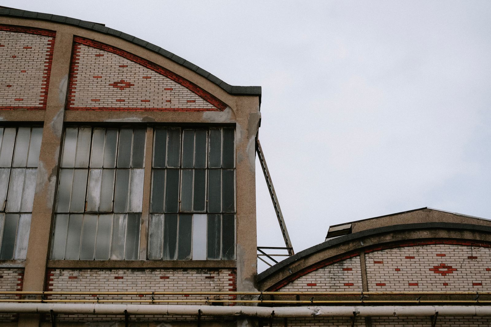a large brick building Brick and steel factory facade with tall industrial windows under an overcast sky