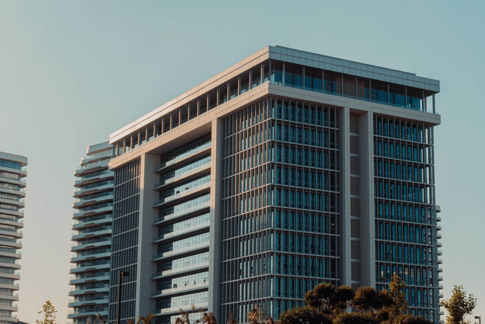 a tall building Mid-rise office tower with a flat roof and glass facade against a clear sky