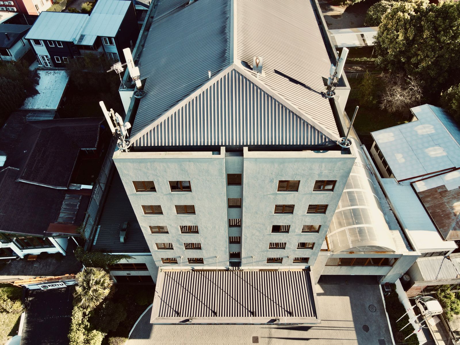 a close up of a building Top-down view of a mid-rise building with a corrugated metal roof and rooftop antennas